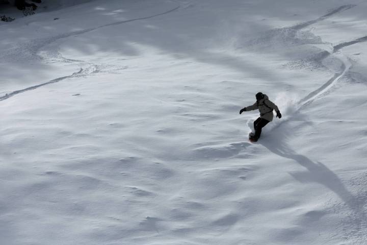 A snowboarder makes turns on fresh snow just after opening at Lee Canyon on Mount Charleston, n ...