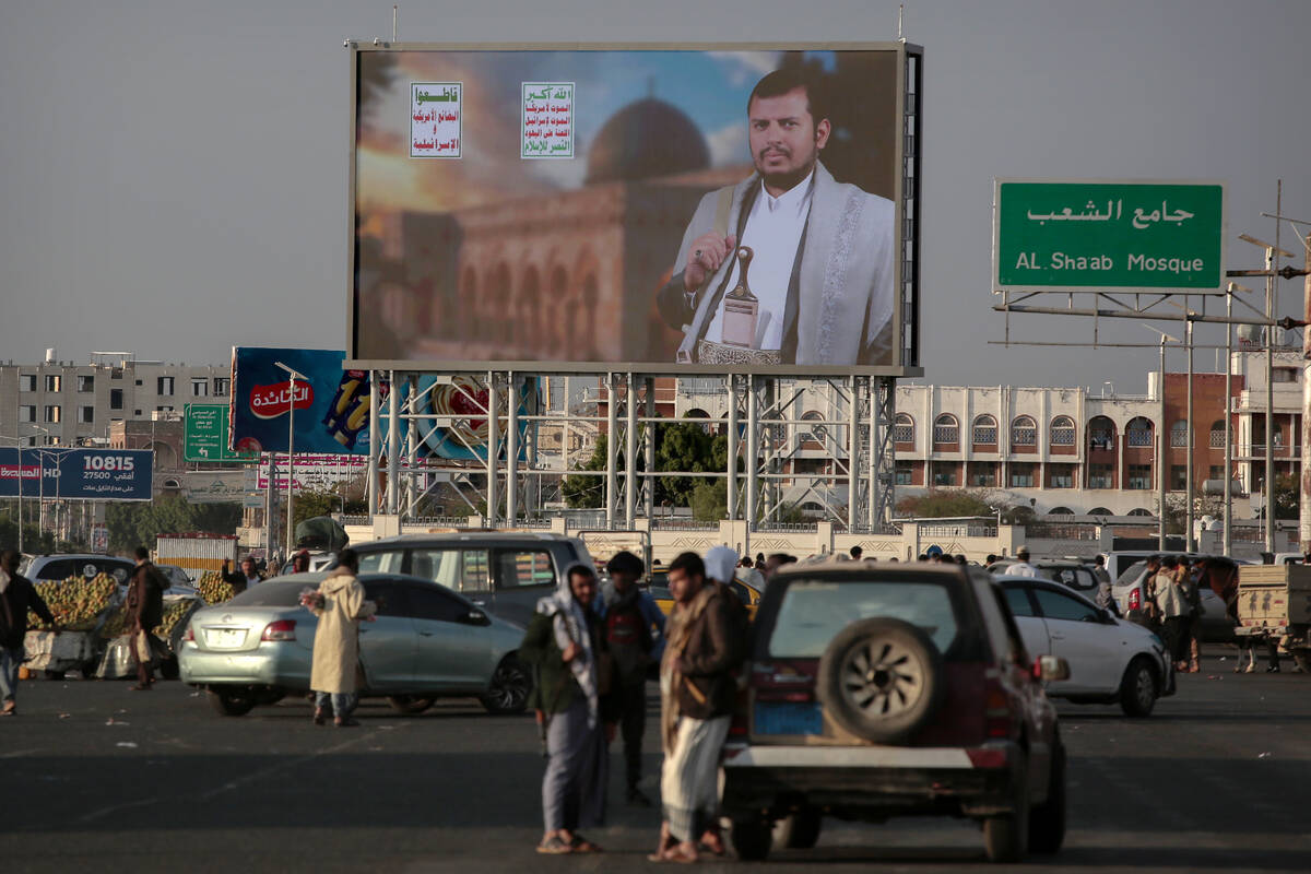 Yemenis stand under a street billboard displaying a picture of Abdul Malik al-Houthi, the leade ...