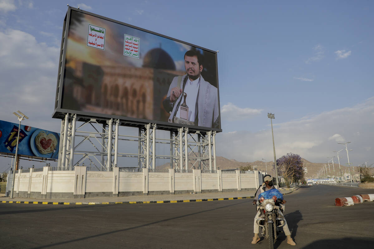 Yemenis pass under a street billboard displaying a picture of Abdul Malik al-Houthi, the leader ...