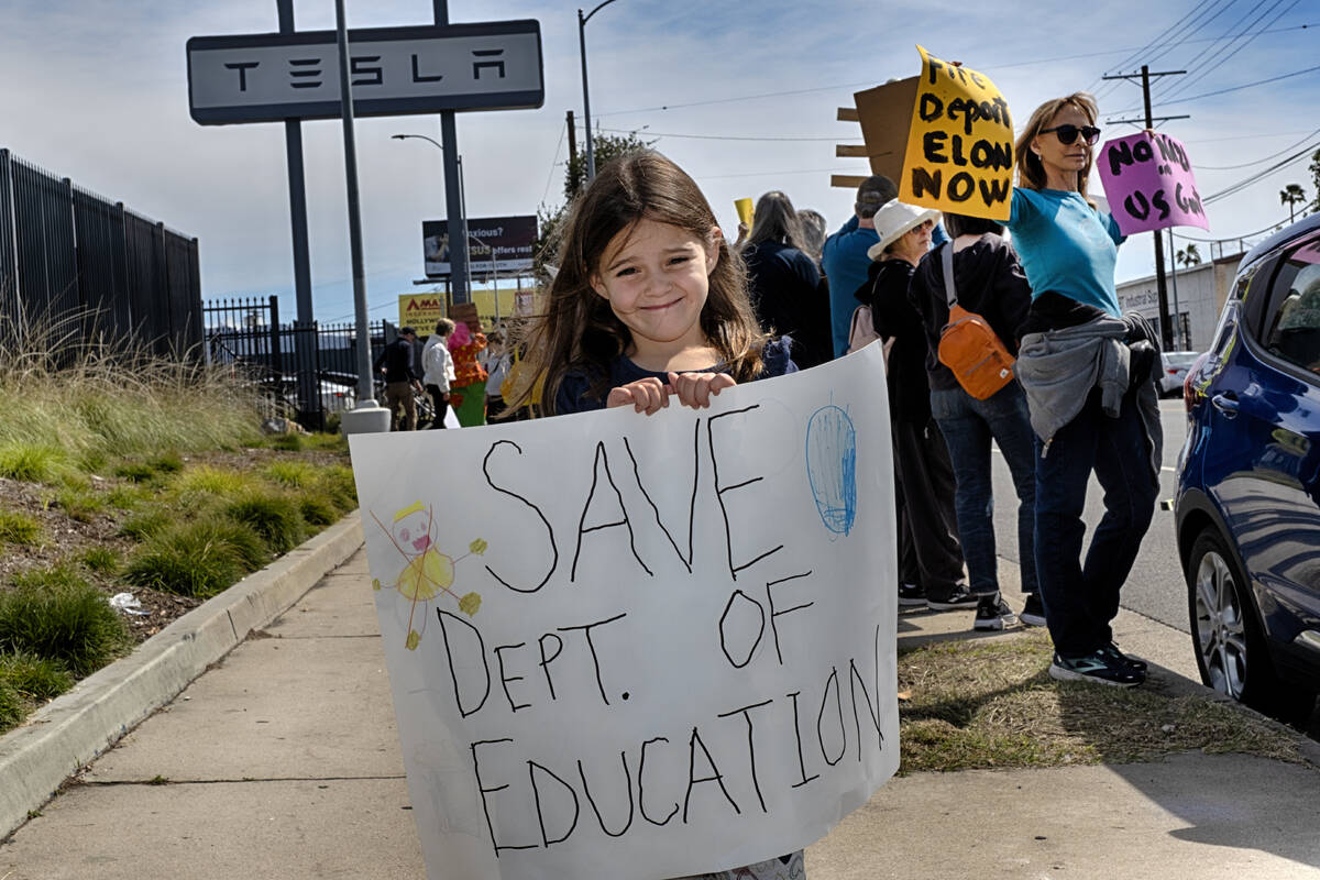 Sarah Cummings carries a protest sign to save the Department of Education while joining other p ...