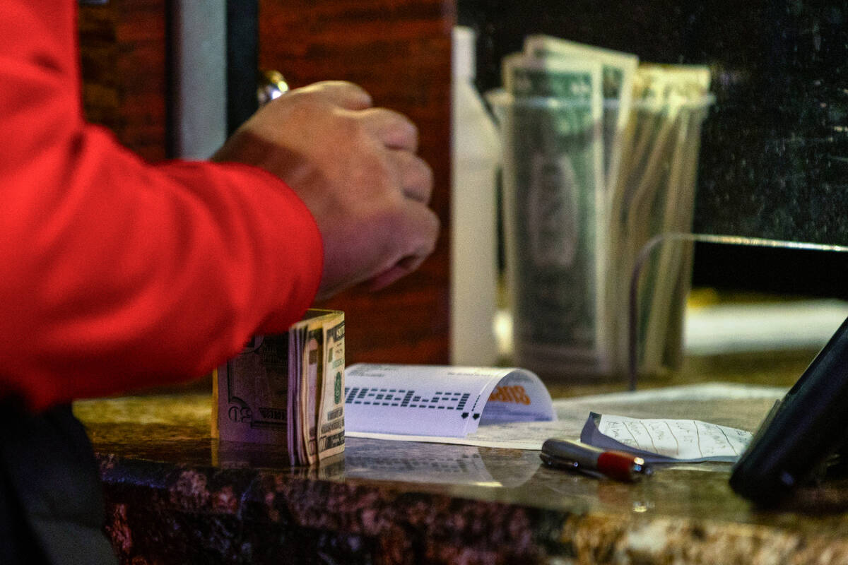 A bettor keeps his cash at the ready as he places his wagers during first day of NCAA Tournamen ...