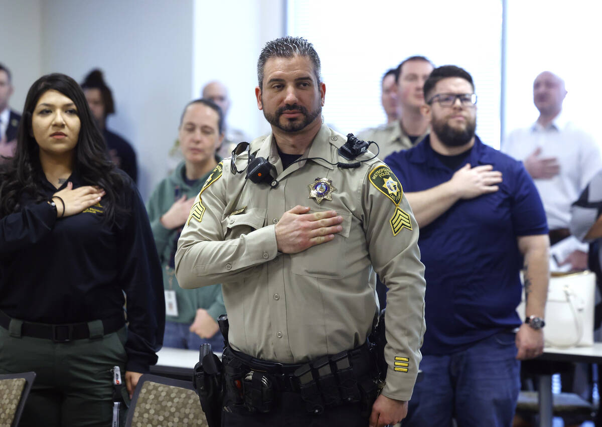 Metro police officers and their families place their hands over their hearts during the Pledge ...