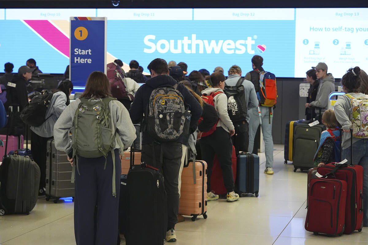 Travelers wait at the check-in counter for Southwest Airlines in Denver International Airport T ...