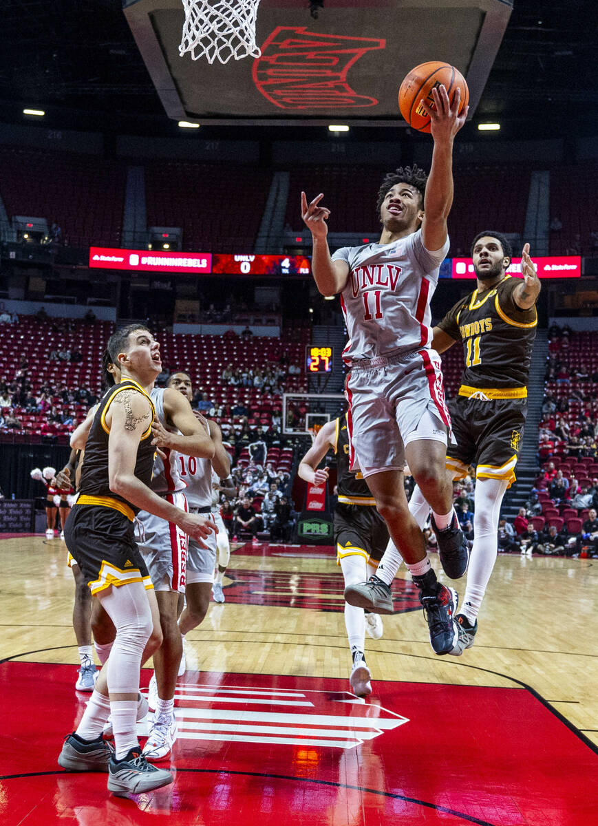 UNLV guard Dedan Thomas Jr. (11) lays the balll in past Wyoming Cowboys guard Dontaie Allen (11 ...