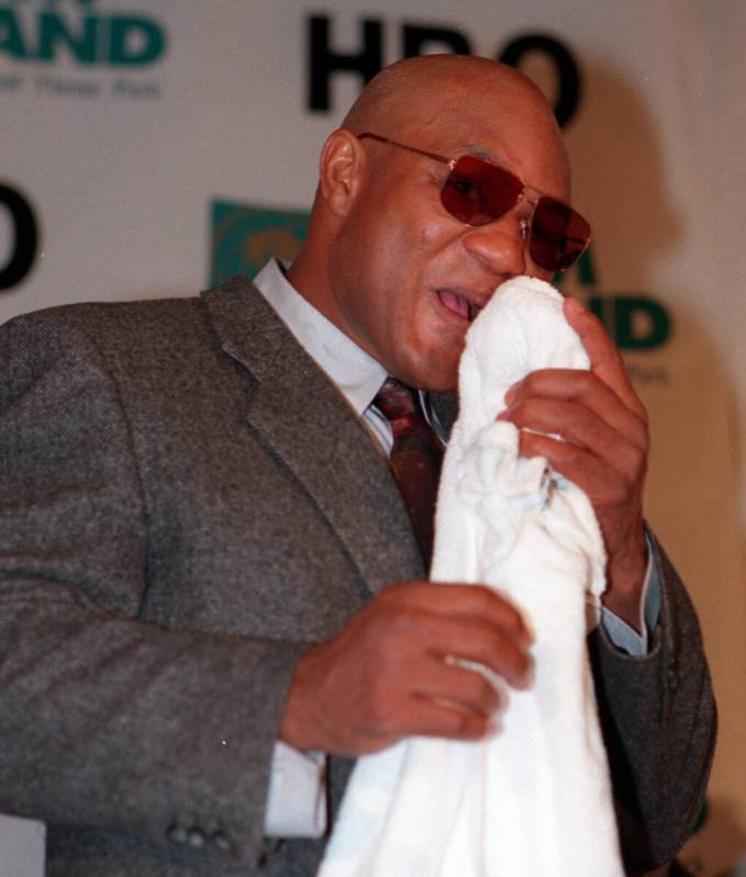 George Foreman applies a cold pack to his lip during the post fight press conference on a Satur ...