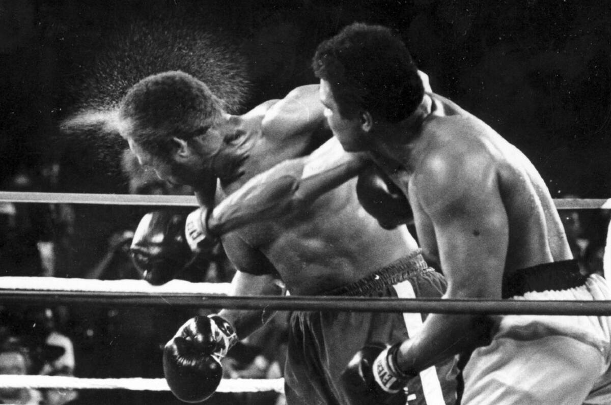 Perspiration flies from the head of George Foreman as he takes a right from challenger Muhammad ...