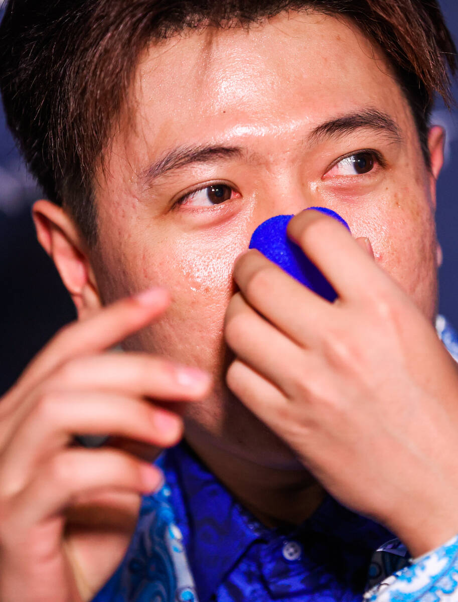 Poseidon Ho, a poker player, puts a blue clown nose on while walking the blue carpet at the One ...