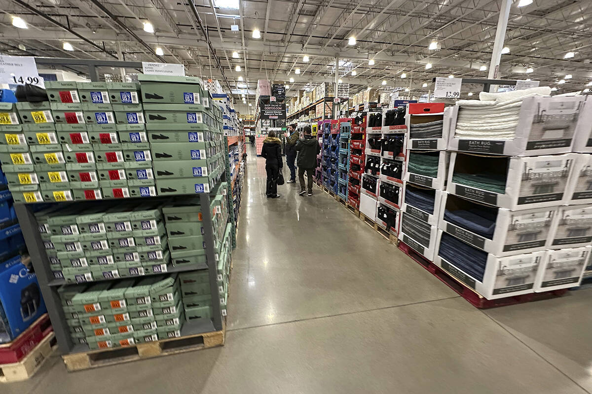 FILE - Shoppers make their ways down an aisle lined with clothing and shoes in a Costco warehou ...