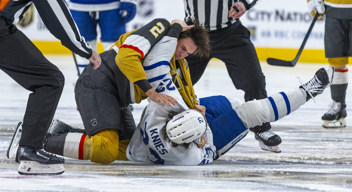 Golden Knights defenseman Zach Whitecloud (2) fights with Toronto Maple Leafs defenseman Simon ...