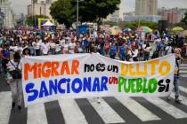 People hold a banner that reads in Spanish, "Migrating is not a crime; sanctioning a peopl ...