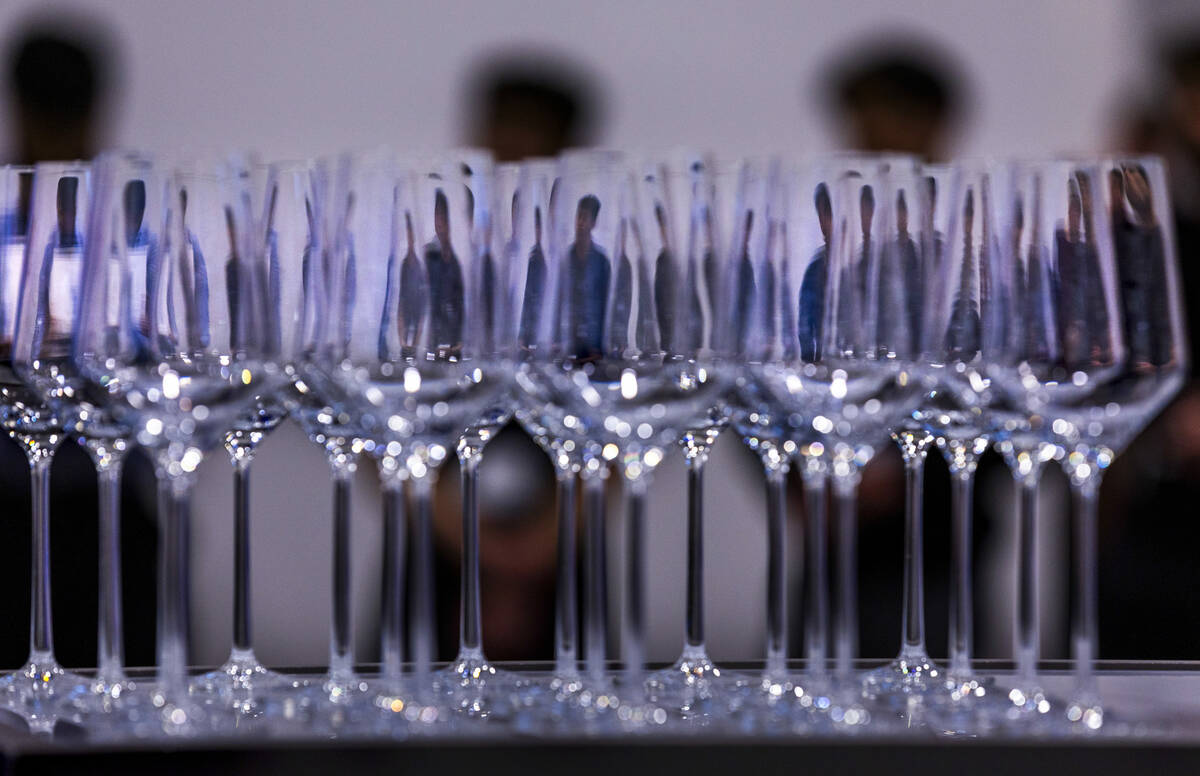 Attendees at Pattern are reflected in wine glasses during a reception and tour of the new distr ...