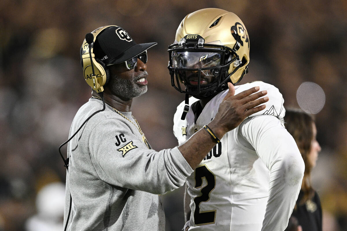 Colorado head coach Deion Sanders, left, talks with quarterback Shedeur Sanders (2) during a ti ...