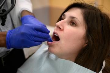 Alexander Daniel, DDS, left, demonstrates fluoride treatment on resident Cameron Onken, right, ...