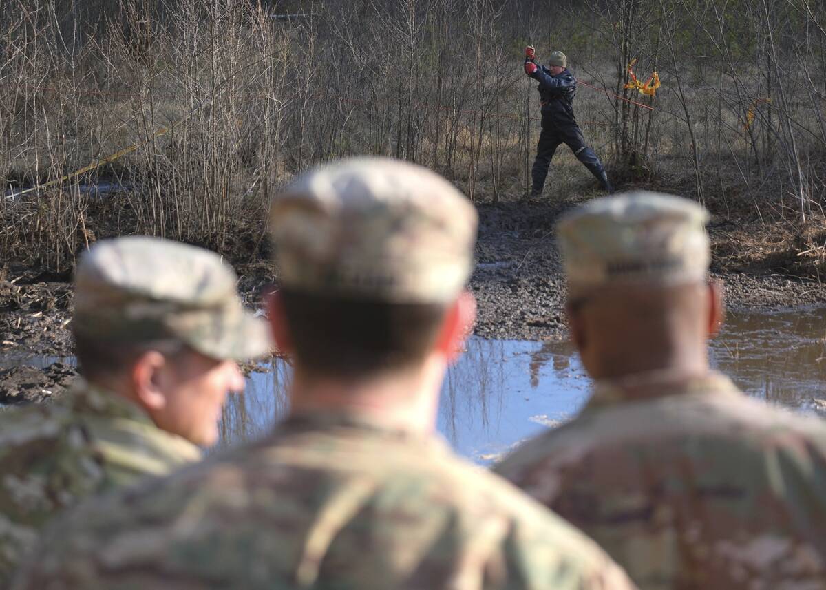 In this image provided by the U.S. Army, a Lithuanian engineer probes through mud for solid gro ...