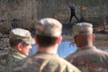 In this image provided by the U.S. Army, a Lithuanian engineer probes through mud for solid gro ...