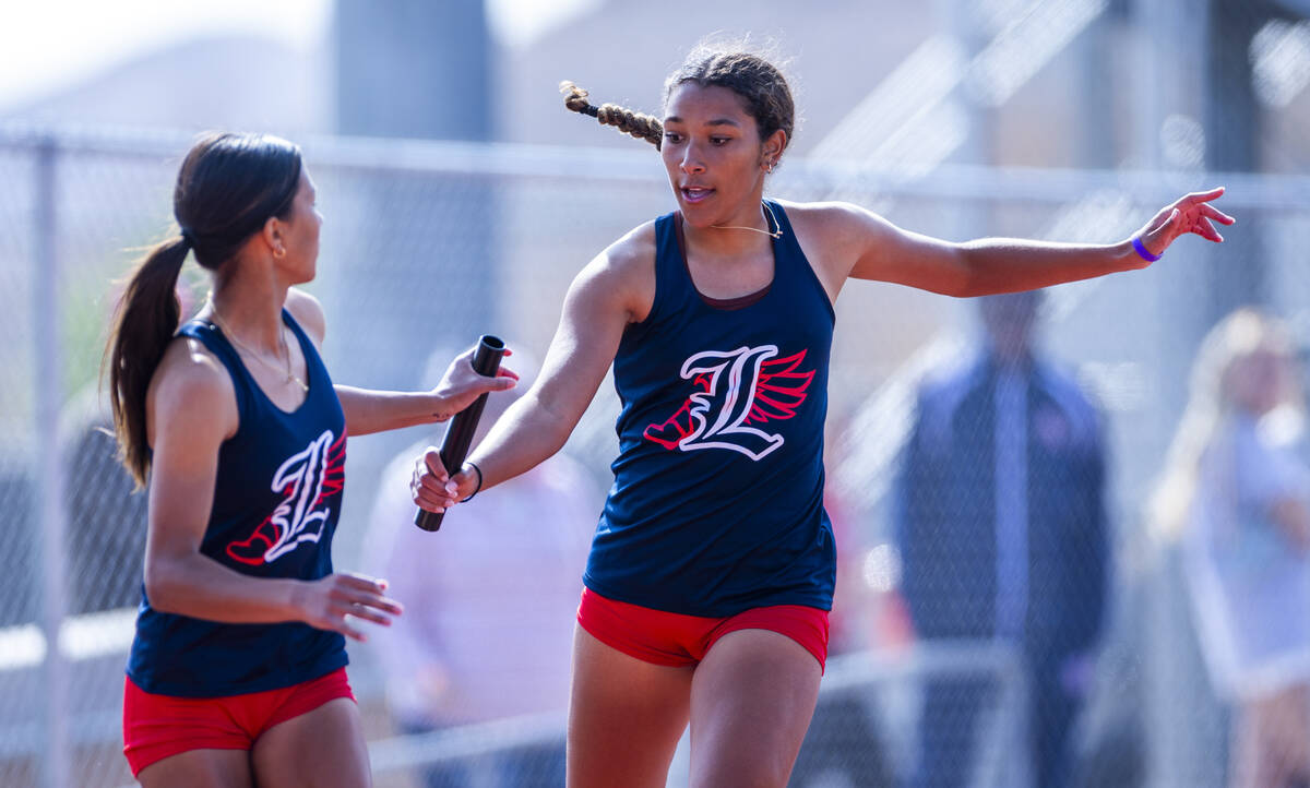Liberty sprinters Trishelle Tucay and Ayva Jordan exchange the baton in the varsity mixed 4x200 ...