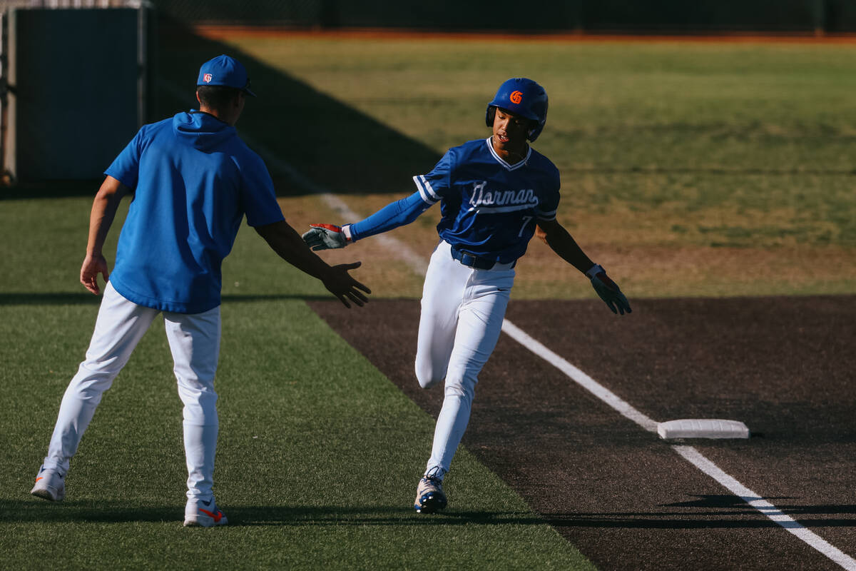 A coach congratulates Bishop Gorman’s Justin Rodrigues (7) as he rounds third base on hi ...
