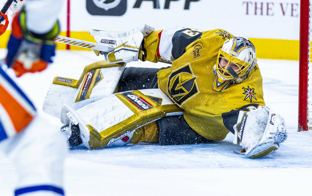 Golden Knights goaltender Adin Hill (33) eyes a puck off his skate from Edmonton Oilers left wi ...