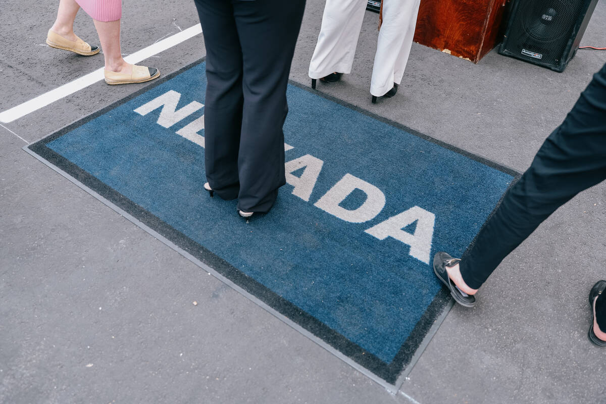 People stand on a Nevada rug as they take pictures of Nevada Governor Joe Lombardo during a pre ...