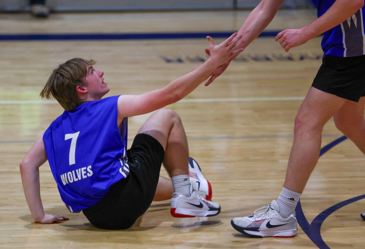 A teammate helps Basic setter Derek Dennett (7) up from the floor after a play during the volle ...
