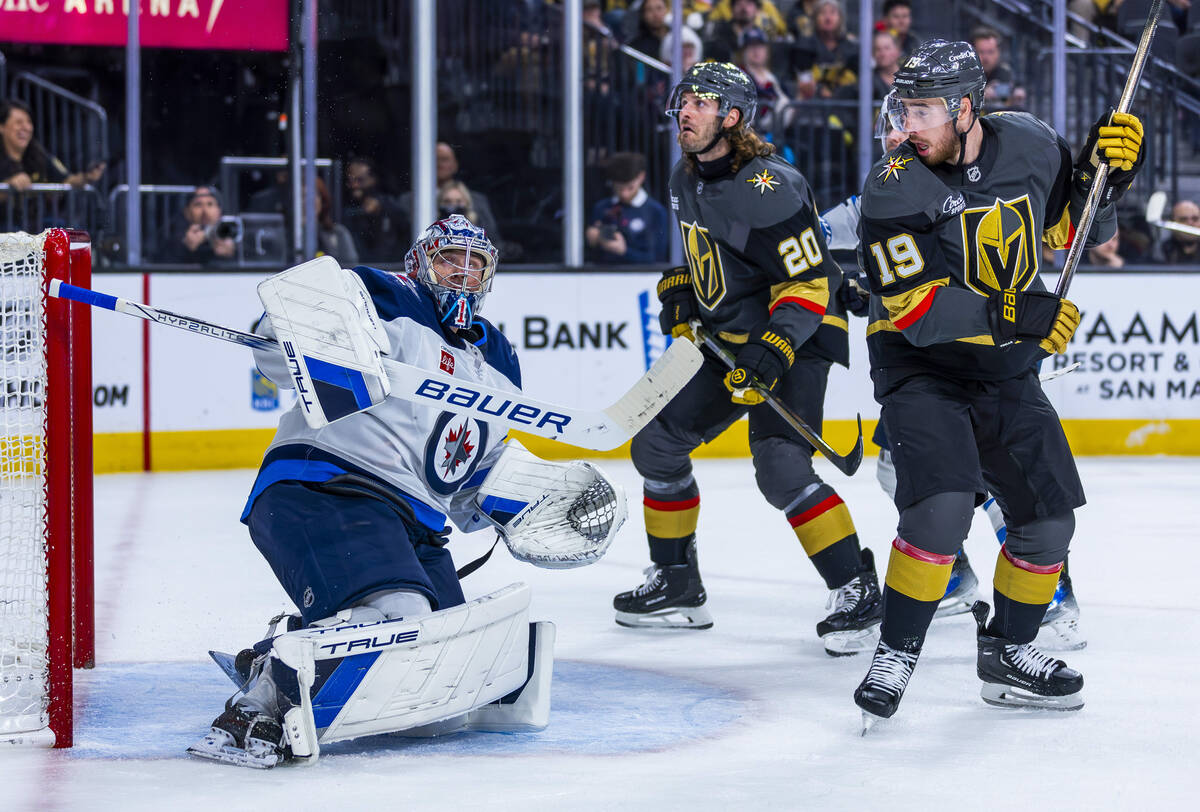 Winnipeg Jets goaltender Eric Comrie (1) looks to a deflected puck along with Golden Knights le ...