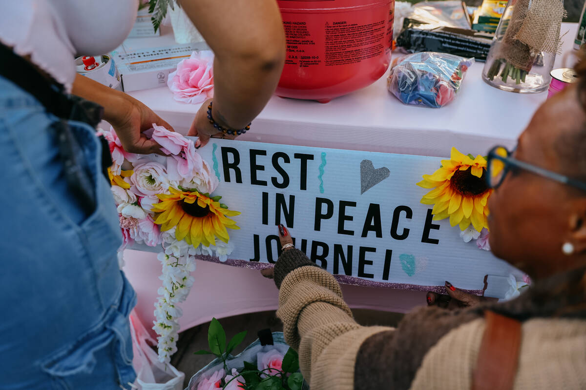 Loved ones tape up a sign for three-year-old Journei Ross during a vigil to commemorate her lif ...