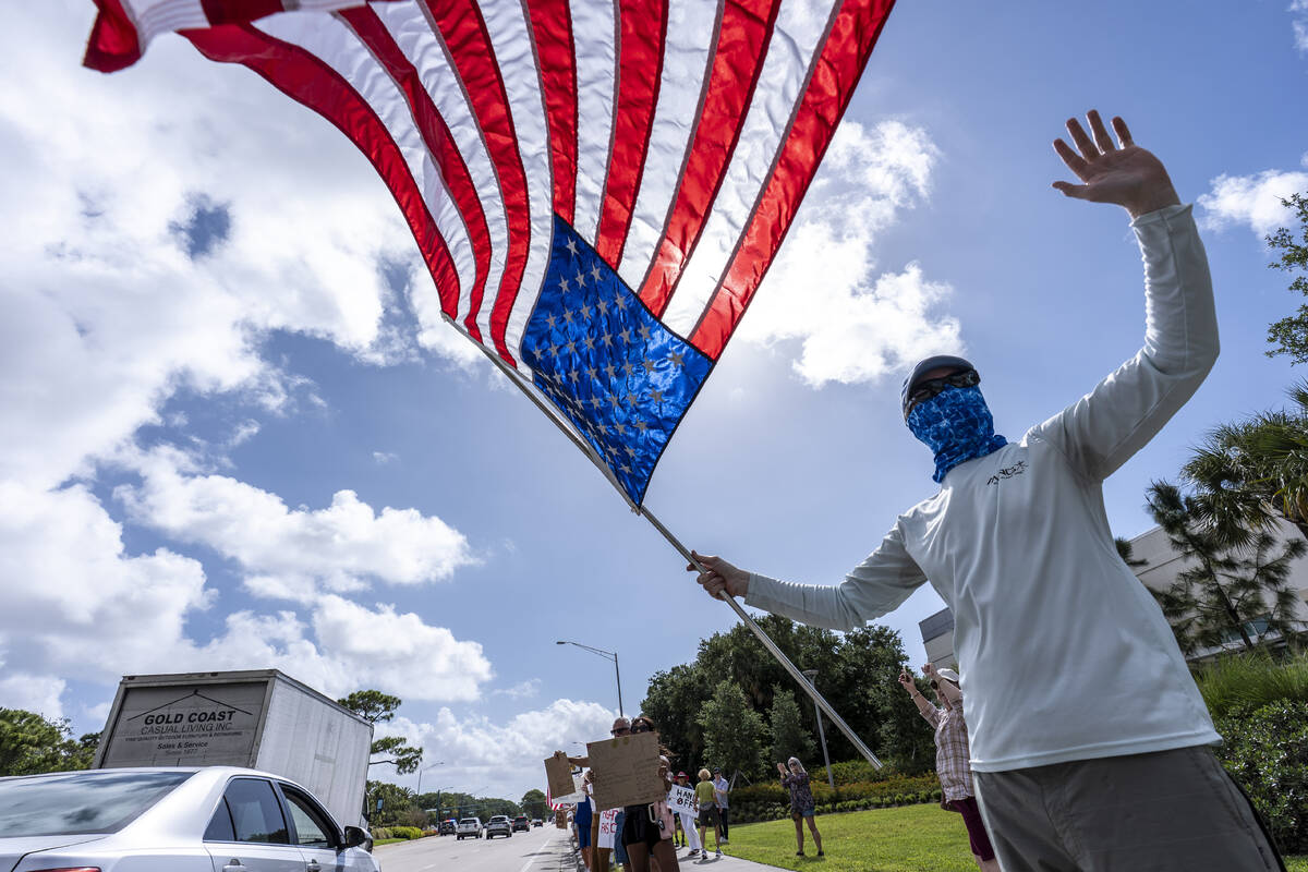 Activists protest President Donald Trump, who was a few miles away at his Trump National Golf C ...