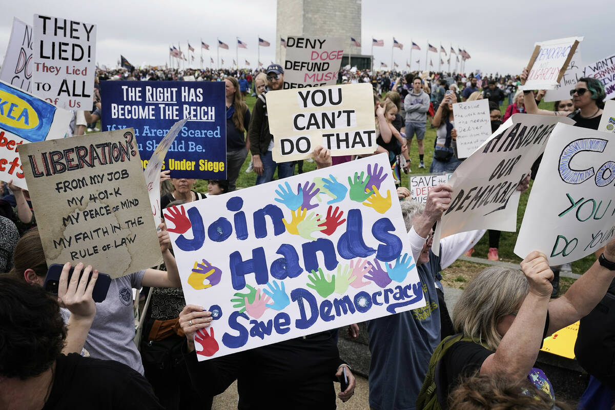 Demonstrators hold up signs during a "Hands Off!" protest against President Donald Tr ...