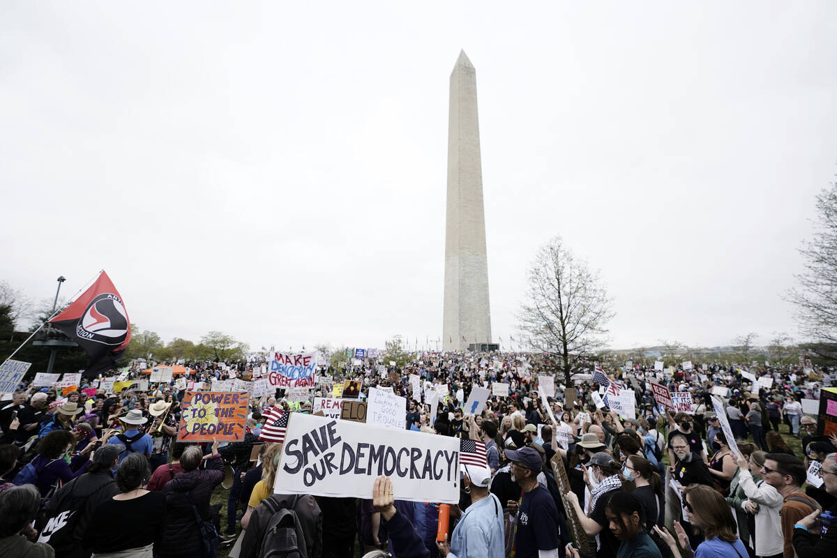 Demonstrators hold up signs during a "Hands Off!" protest against President Donald Tr ...