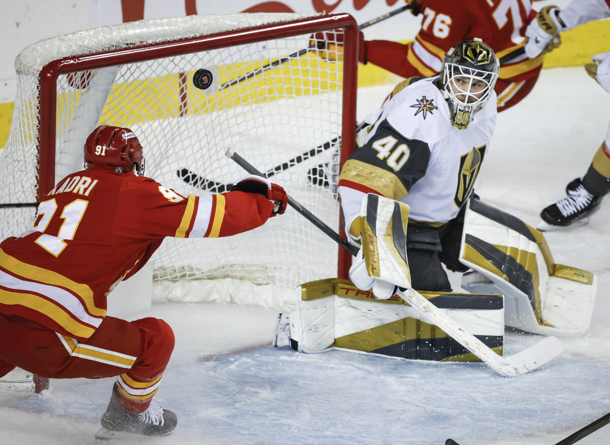 Vegas Golden Knights goalie Akira Schmid, right, looks on as Calgary Flames' Nazem Kadri tires ...