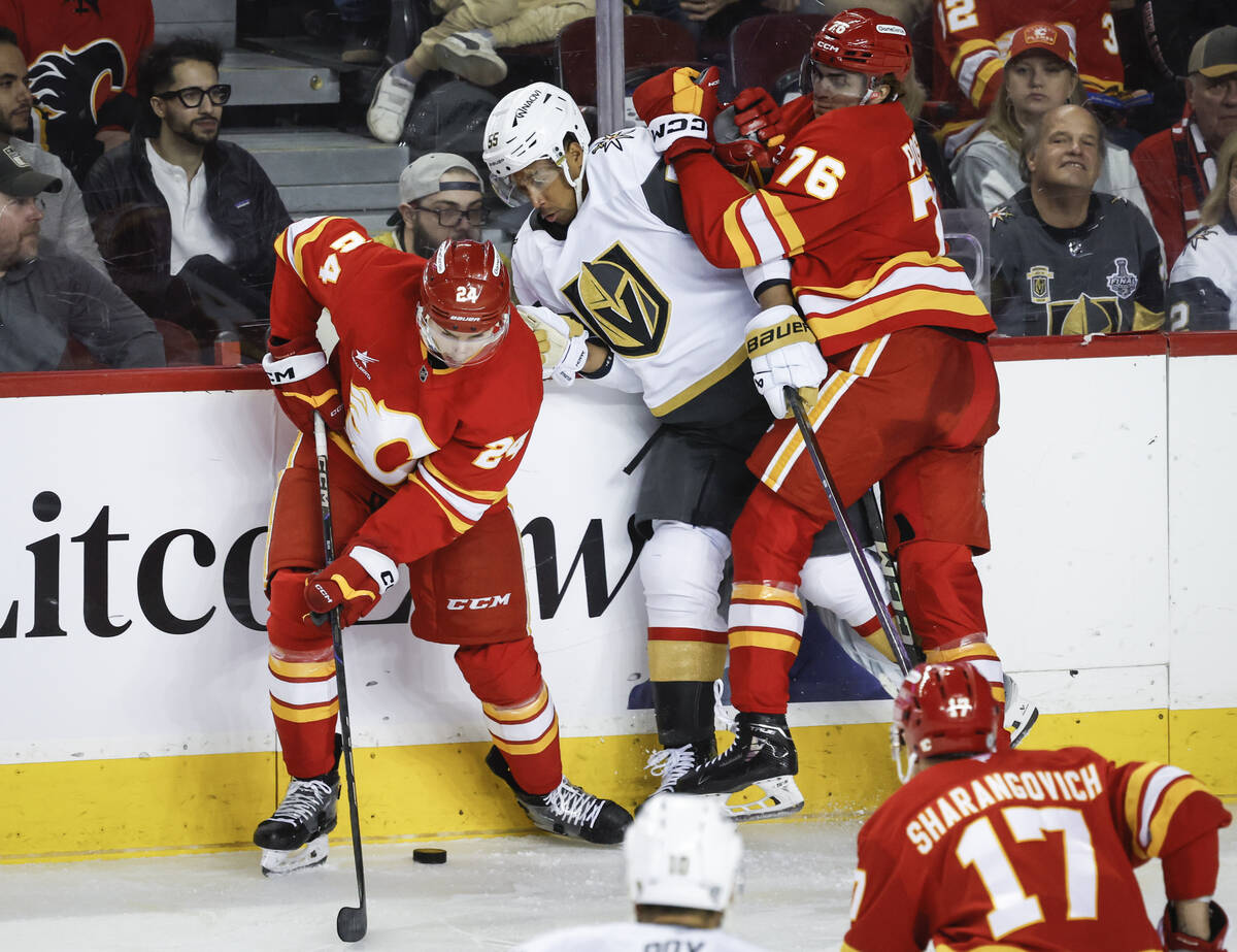 Vegas Golden Knights' Keegan Kolesar, centre, is checked by Calgary Flames' Martin Pospisil, ri ...