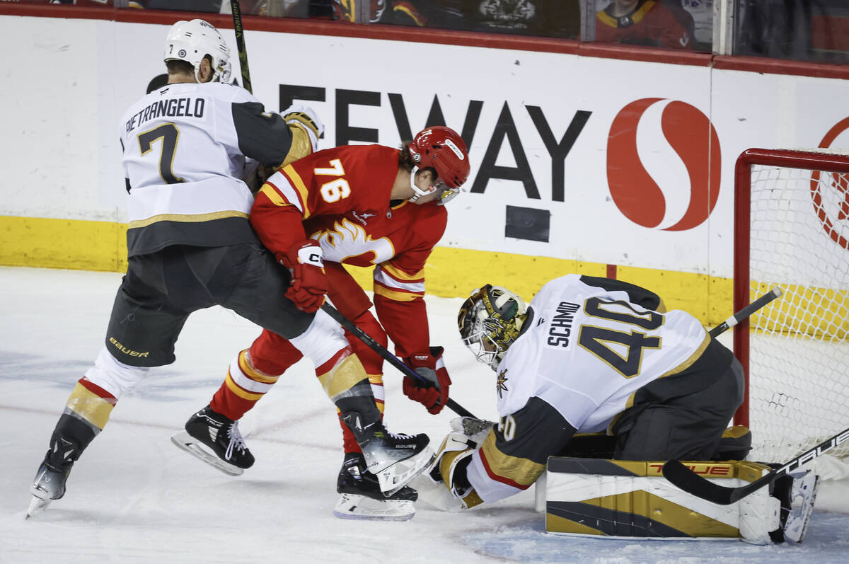Vegas Golden Knights goalie Akira Schmid, right, grabs the puck as Calgary Flames' Martin Pospi ...