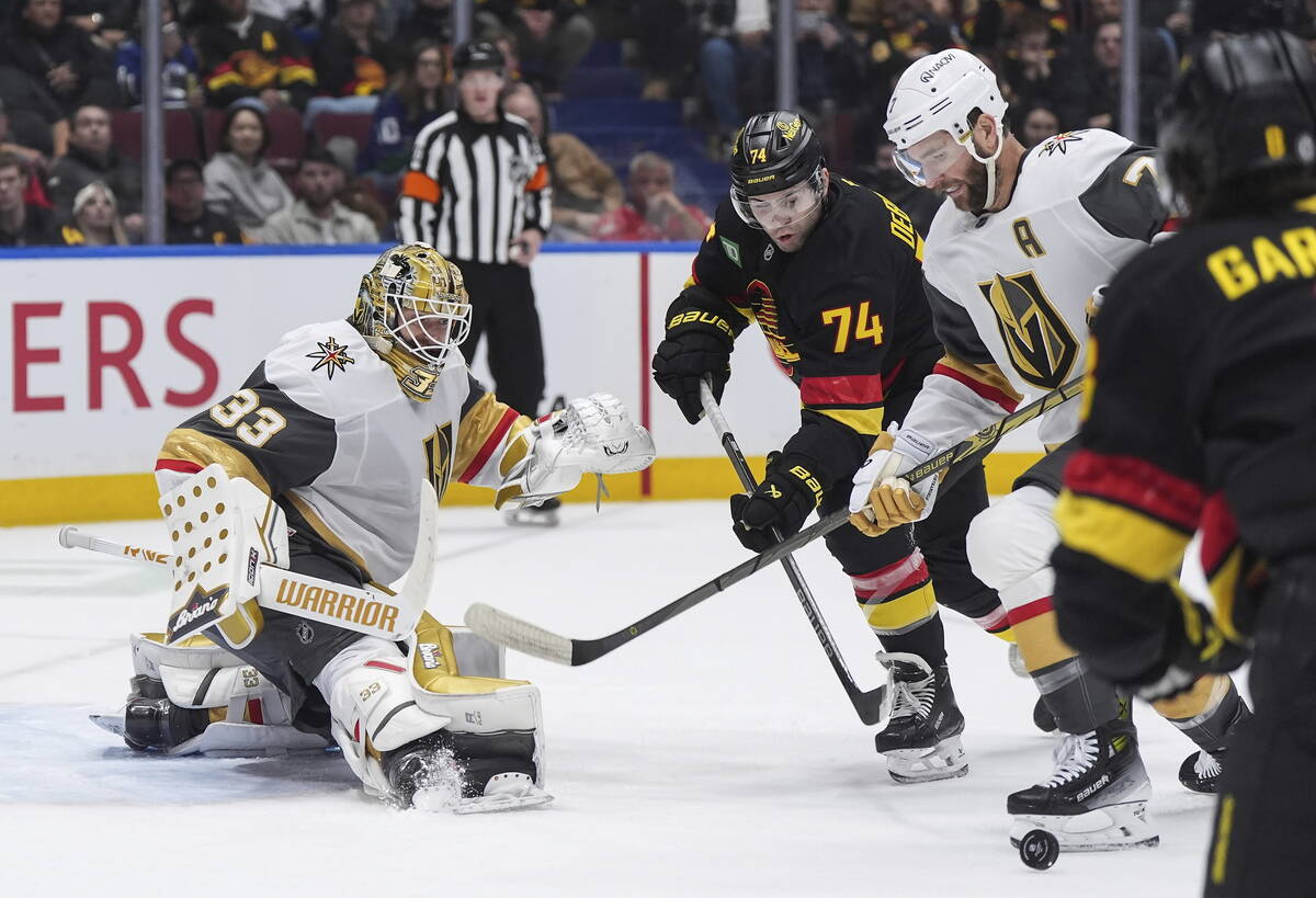 Vancouver Canucks' Jake DeBrusk (74) and Vegas Golden Knights' Alex Pietrangelo, right, vie for ...