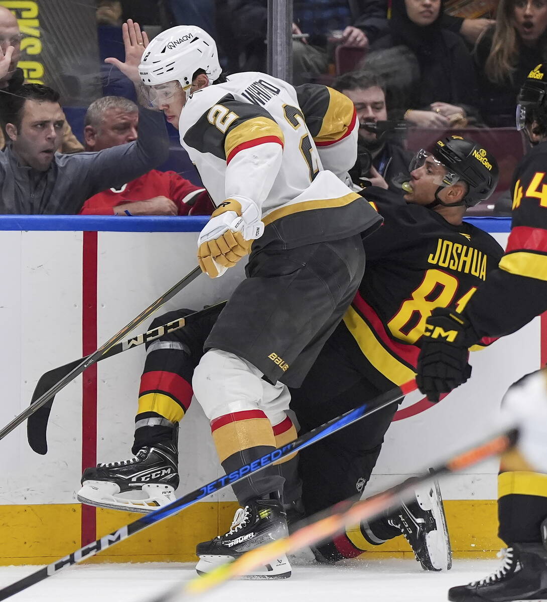 Vegas Golden Knights' Zach Whitecloud (2) checks Vancouver Canucks' Dakota Joshua (81) during t ...