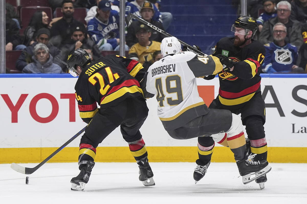 Vancouver Canucks' Filip Hronek (17) checks Vegas Golden Knights' Ivan Barbashev (49) as Canuck ...