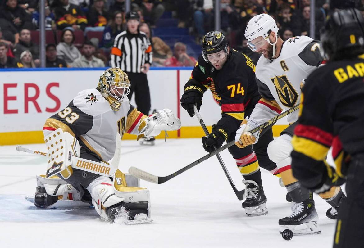 Vancouver Canucks' Jake DeBrusk (74) and Vegas Golden Knights' Alex Pietrangelo, right, vie for ...