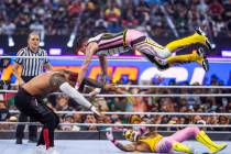 Jimmy Uso, left, has Rey Mysterio, top right, jump down on top of him with Dominik Mysterio bel ...