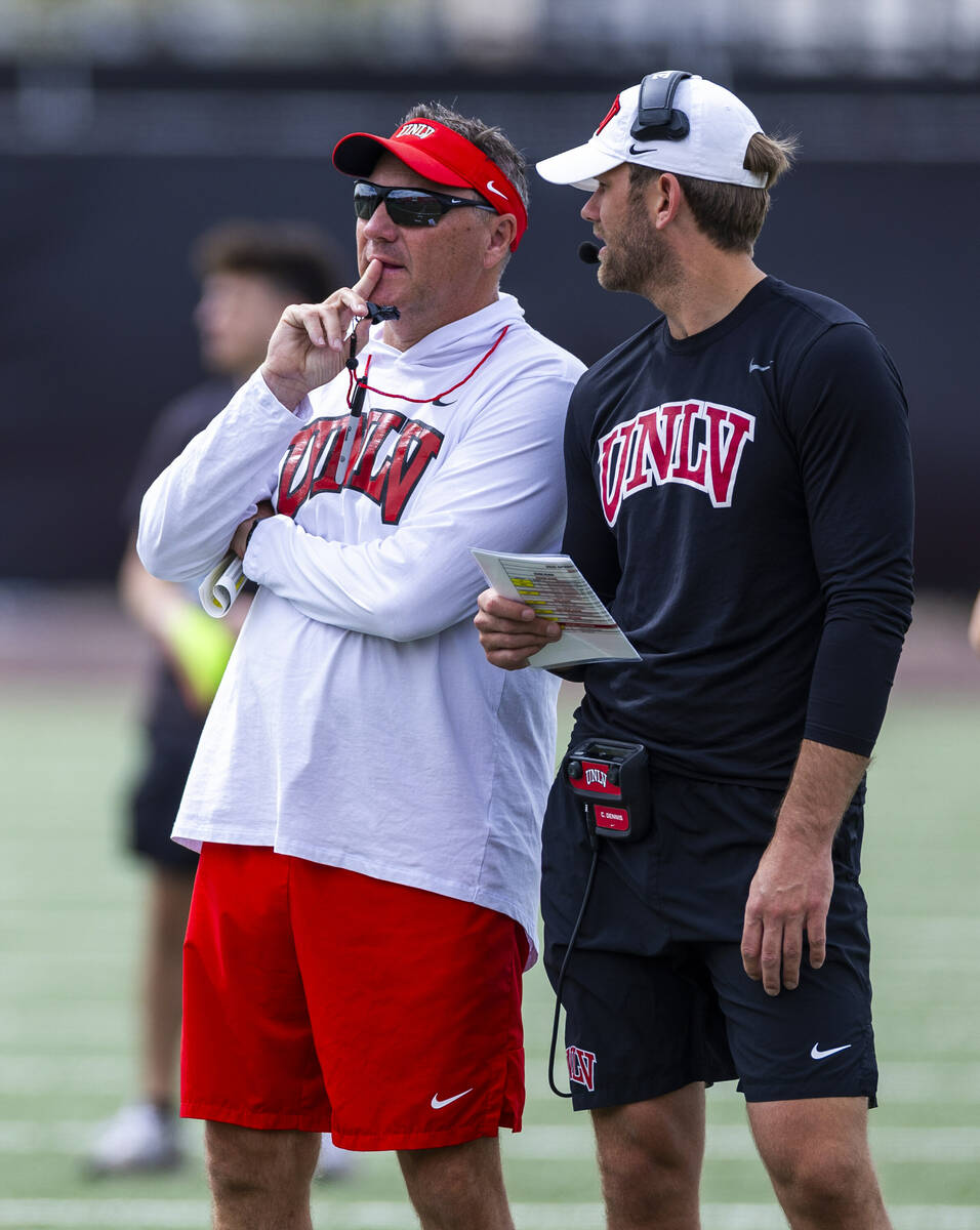 UNLV head coach Dan Mullen talks with offensive coordinator/quarterbacks coach Corey Dennis dur ...