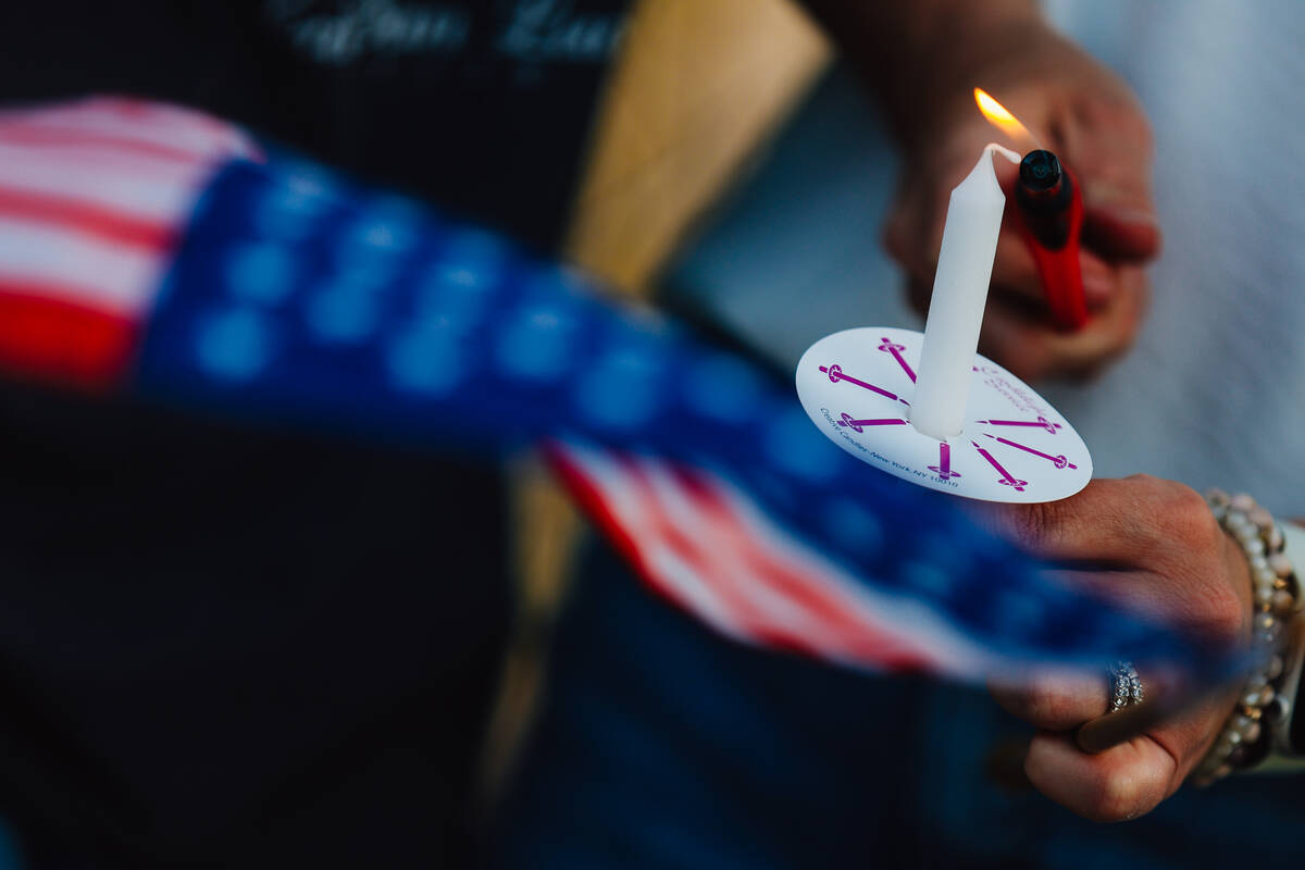 A mourner holds a flag and lights a candle during a vigil for Jordon Dodder, who died after a c ...