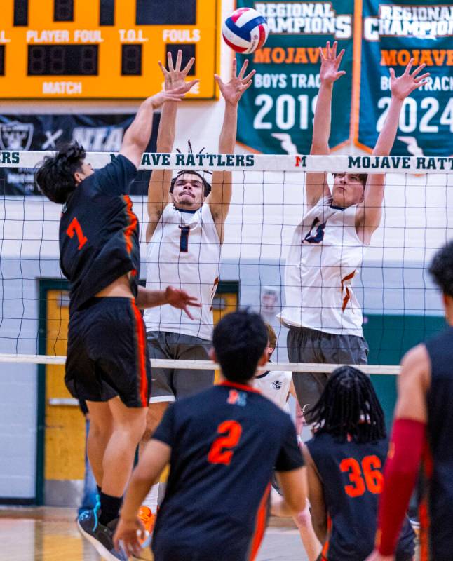 Mojave's Jhoemel Bagalawis (7) spikes the ball past Legacy's Isaiah Moore (1) and Cambel Tolman ...