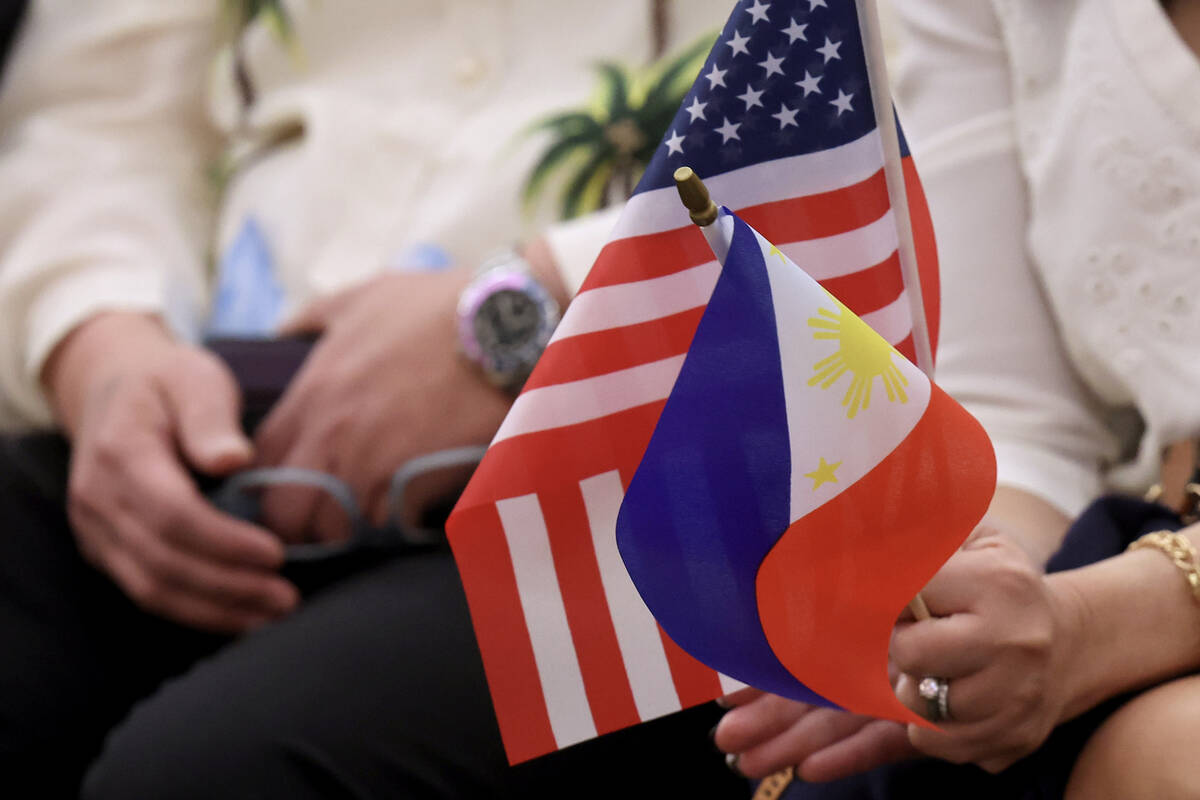 An audience member holds Filipino and American flags during a Clark County Commission meeting w ...