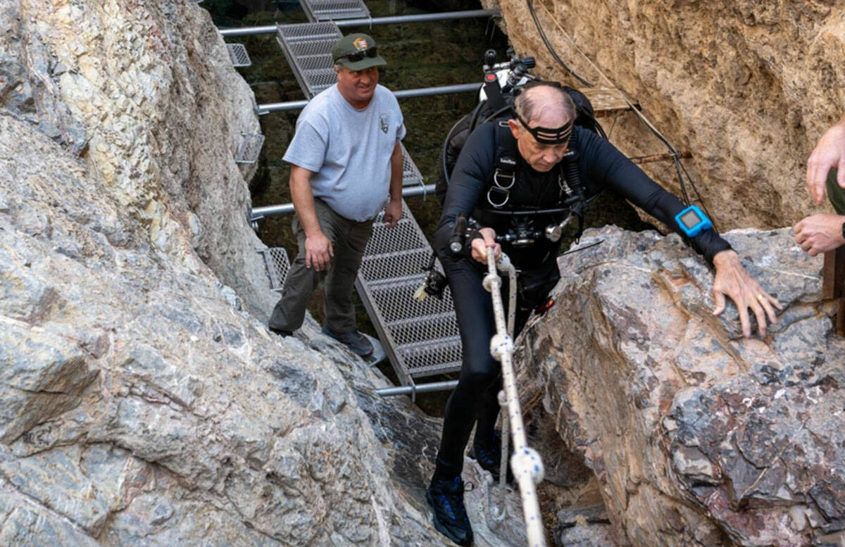 National Park Service biologist Kevin Wilson helps volunteer-in-park diver Mal Maloney traverse ...