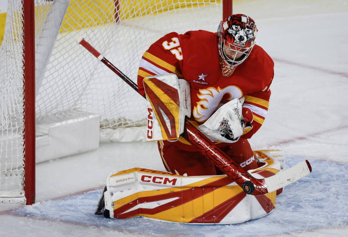 Calgary Flames goalie Dustin Wolf (32) gets his stick on a shot from the Vegas Golden Knights d ...