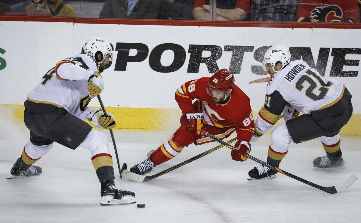 Vegas Golden Knights' Nicolas Hague (4) and Brett Howden (21) check Calgary Flames' Joel Farabe ...