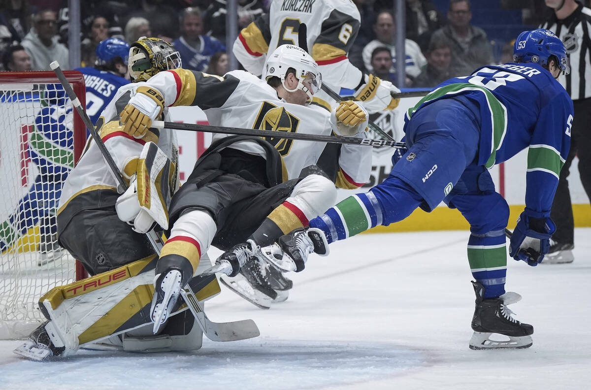 Vegas Golden Knights' Ben Hutton, front left, falls in front of goalie Akira Schmid while tryin ...