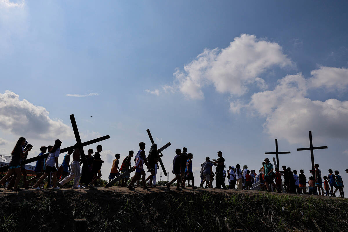 Filipino penitents carry their crosses atop the crucifixion mound during Good Friday rituals in ...