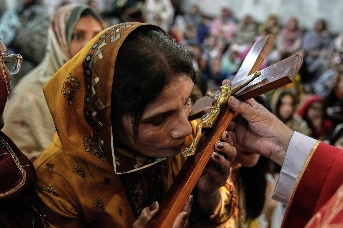 A Christian woman kisses the cross during a service at St. Anthony Church, marking Good Friday, ...