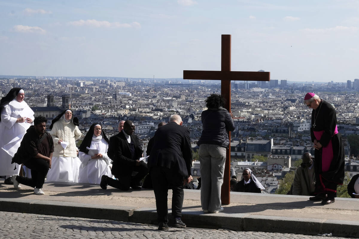 Paris Archbishop Laurent Ulrich, right, leans to the cross during the Way of Cross ceremony to ...