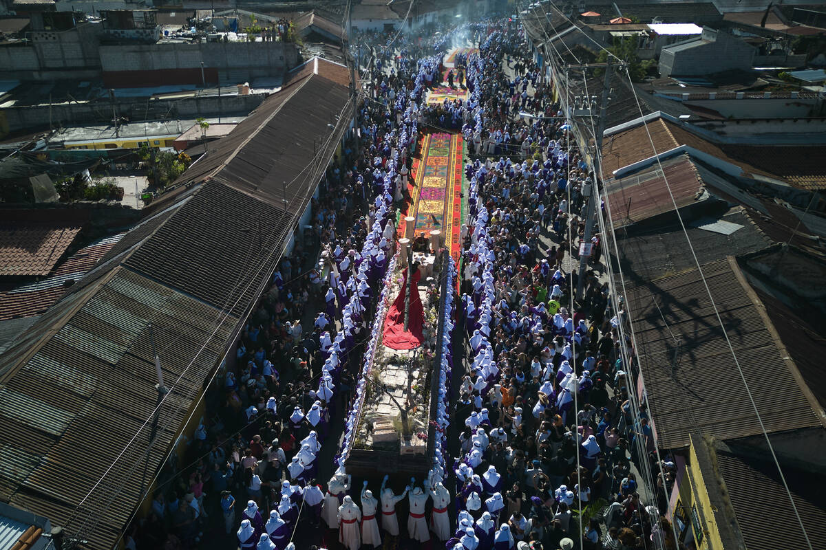 Penitents knows as "cucuruchos" carry a statue of Jesus Christ bearing a cross, durin ...