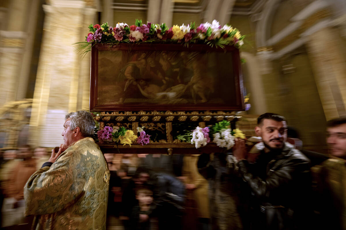 People carry a wooden structure decorated with flowers depicting the coffin of Jesus Christ dur ...